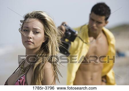 Young man photographing woman in swimsuit View Large Photo Image Stock Photograph - Young man photographing woman in swimsuit. Fotosearch