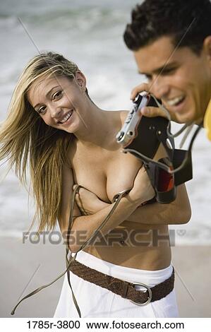 Young man photographing woman undressing at the beach View Large Photo Image Stock Image - Young man photographing woman undressing at the beach. Fotosearch