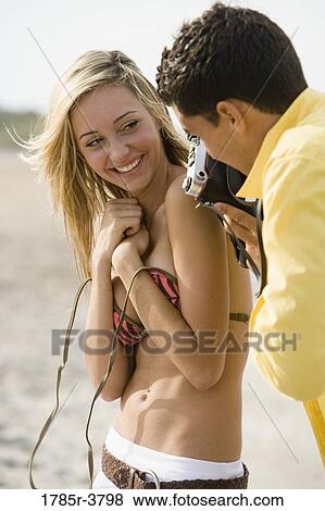 Young man photographing woman undressing at the beach View Large Photo Image Stock Photo - Young man photographing woman undressing at the beach. Fotosearch
