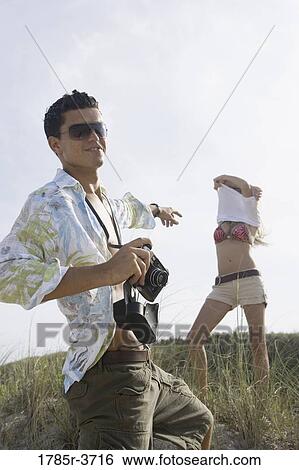 Young man pointing at a woman undressing View Large Photo Image Stock Photograph - Young man pointing at a woman undressing. Fotosearch