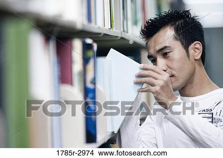 Young man removing book from library bookshelf View Large Photo Image Picture - Young man removing book from library bookshelf. Fotosearch