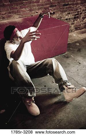 Young man sitting on floor gesturing View Large Photo Image Stock Photo - Young man sitting on floor gesturing. Fotosearch