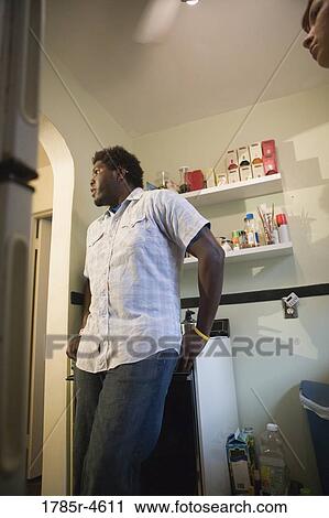 Young man standing in a kitchen View Large Photo Image Stock Image - Young man standing in a kitchen. Fotosearch
