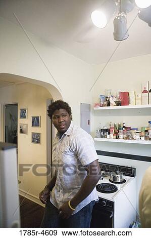 Young man standing in a kitchen View Large Photo Image Stock Photo - Young man standing in a kitchen. Fotosearch