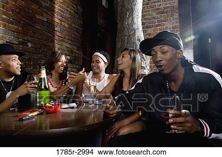 Young men and women in hip-hop fashion partying at a bar View Large Photo Image Picture - Young men and women in hip-hop fashion partying at a bar. Fotosearch