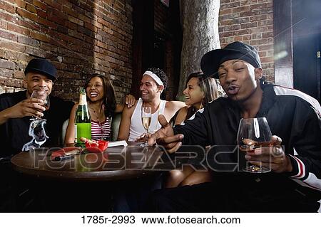 Stock Image - Young men and women in hip-hop fashion partying at a bar. Fotosearch