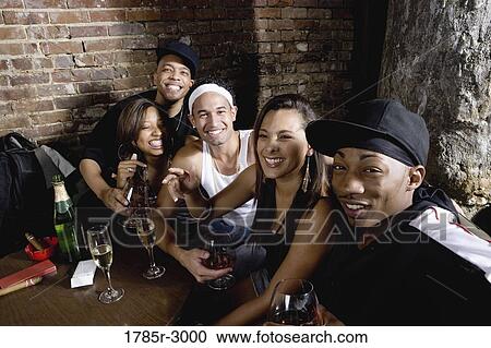 Stock Image - Young men and women in hip-hop fashion partying at a bar. Fotosearch
