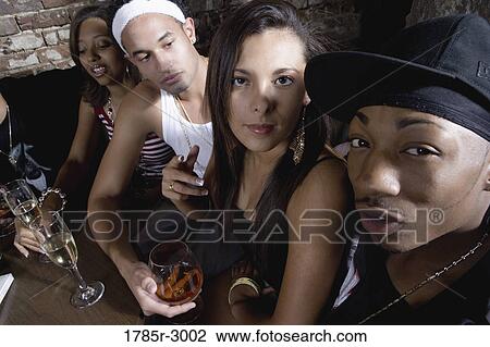 Stock Image - Young men and women in hip-hop fashion partying at a bar. Fotosearch