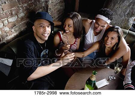 Stock Photo - Young men and women in hip-hop fashion partying at a bar. Fotosearch