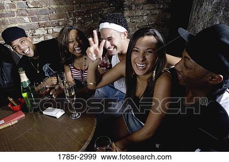 Stock Photo - Young men and women in hip-hop fashion partying at a bar. Fotosearch
