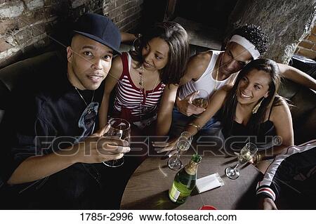Stock Photograph - Young men and women in hip-hop fashion partying at a bar. Fotosearch