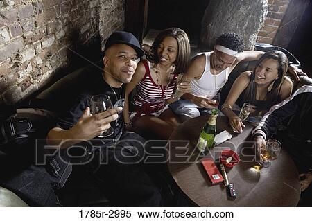 Stock Photography - Young men and women in hip-hop fashion partying at a bar. Fotosearch