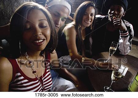 Stock Photography - Young men and women in hip-hop fashion partying at a bar. Fotosearch