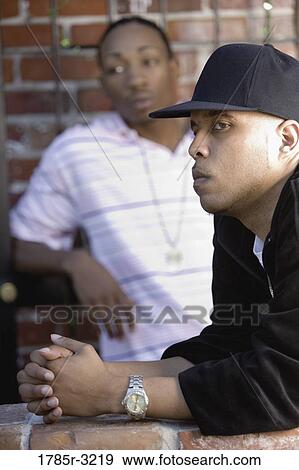 Stock Photo - Young men in hip-hop fashion hanging out in back alley. Fotosearch