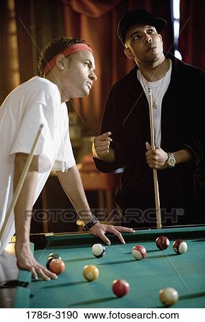 Young men playing billiards in pool hall View Large Photo Image Stock Image - Young men playing billiards in pool hall. Fotosearch