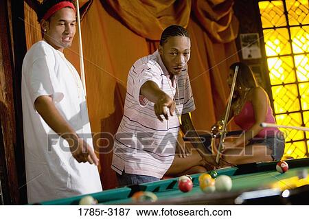 Stock Photo - Young men playing billiards in pool hall. Fotosearch