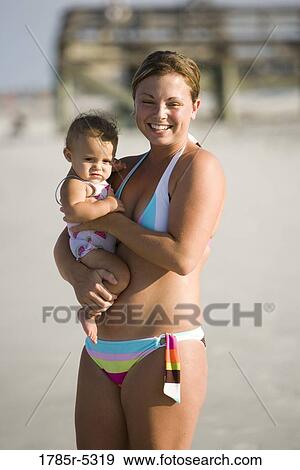 Young mother holding baby at the beach View Large Photo Image Stock Photo - Young mother holding baby at the beach. Fotosearch