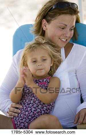 Young mother with daughter sitting on beach chair View Large Photo Image Picture - Young mother with daughter sitting on beach chair. Fotosearch