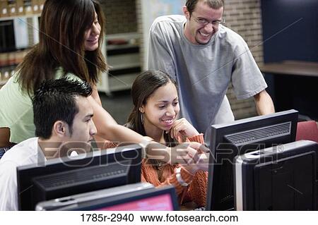Stock Image - Young students pointing towards a computer monitor. Fotosearch