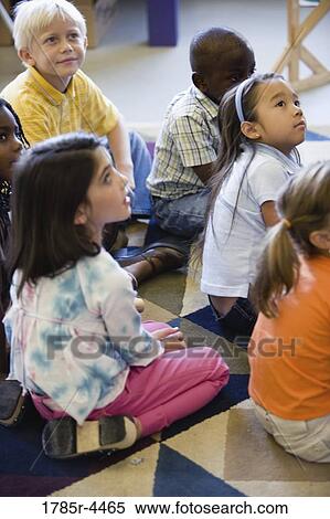 Young students seated on floor watching and listening attentively View Large Photo Image Stock Photography - Young students seated on floor watching and listening attentively. Fotosearch