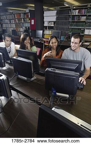 Picture - Young students using computers in the library. Fotosearch