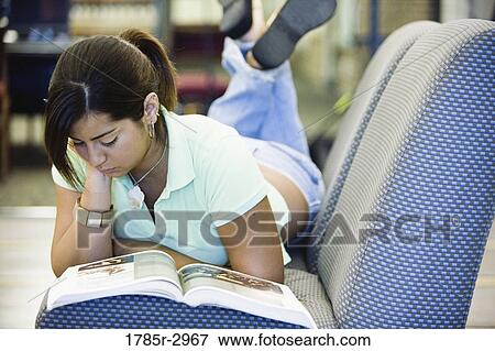 Young woman lying on the sofa reading a book View Large Photo Image Stock Photo - Young woman lying on the sofa reading a book. Fotosearch