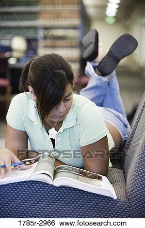 Young woman lying on the sofa reading a book View Large Photo Image Stock Photograph - Young woman lying on the sofa reading a book. Fotosearch
