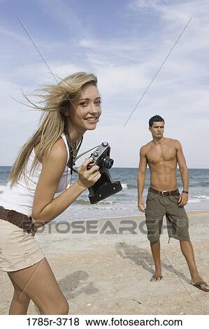 Young woman photographing a man at the beach View Large Photo Image Stock Photo - Young woman photographing a man at the beach. Fotosearch
