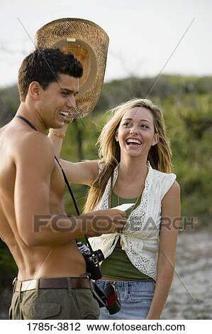 Young woman playing with hat on a man's head View Large Photo Image Stock Image - Young woman playing with hat on a man's head. Fotosearch