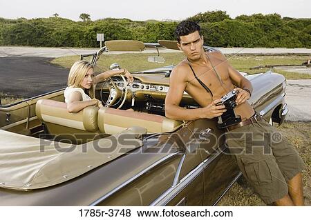 Young woman sitting in antique convertible car being photographed by a man View Large Photo Image Stock Photo - Young woman sitting in antique convertible car being photographed by a man. Fotosearch