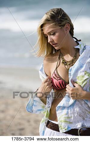 Young woman taking her shirt off standing on beach View Large Photo Image Picture - Young woman taking her shirt off standing on beach. Fotosearch