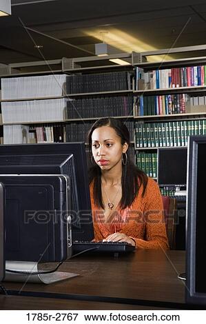 Stock Photo - Young woman using a computer in the library. Fotosearch