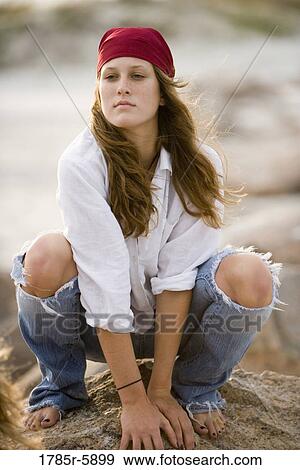 Young woman with bandana crouching on rock View Large Photo Image Stock Photo - Young woman with bandana crouching on rock. Fotosearch