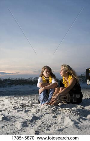 Young women sitting on sand at beach View Large Photo Image Stock Image - Young women sitting on sand at beach. Fotosearch