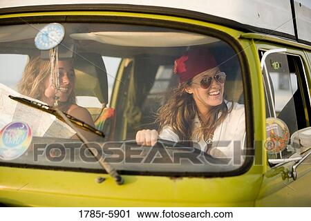 Stock Image - Young women smiling while driving van. Fotosearch