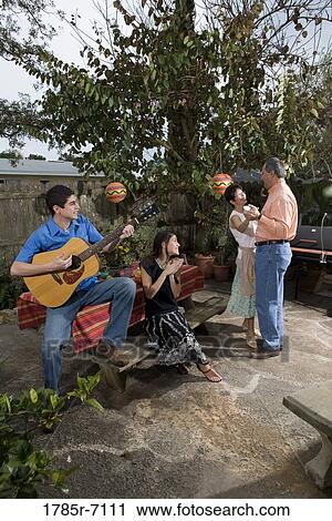 Stock Image - A Mexican-American family playing music and dancing in the backyard of their house. Fotosearch