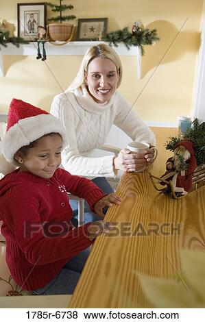A mother sitting with her young daughter at a kitchen counter View Large Photo Image Stock Photo - A mother sitting with her young daughter at a kitchen counter. Fotosearch