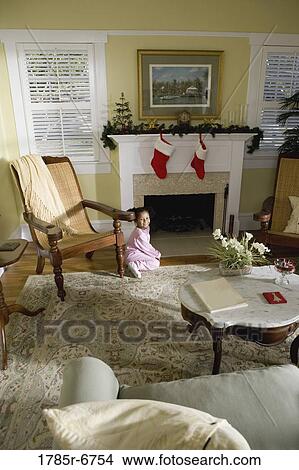 Picture - A young girl in pajamas by the fireplace waiting for Santa. Fotosearch