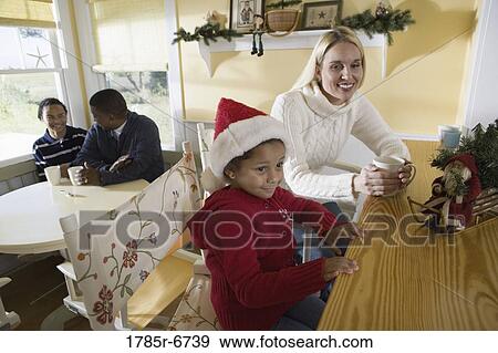 Stock Photo - An inter-racial family sitting at the kitchen counter and table. Fotosearch
