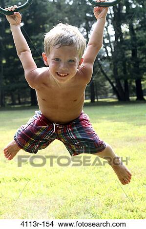 Boy hanging on gymnastic rings in a park View Large Photo Image Picture - Boy hanging on gymnastic rings in a park. Fotosearch