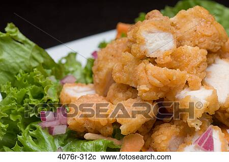 Stock Image - Breaded chicken with onion on lettuce leaves. Fotosearch