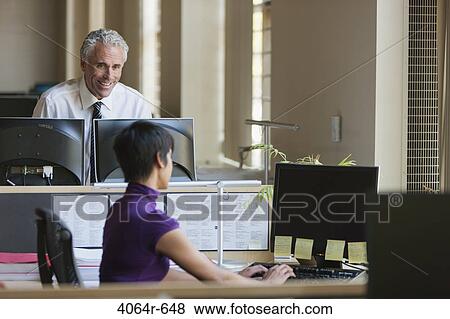 Businessman and woman talking at desks in office View Large Photo Image Stock Photo - Businessman and woman talking at desks in office. Fotosearch