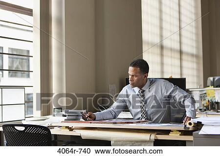 Businessman at desk in office View Large Photo Image Stock Image - Businessman at desk in office. Fotosearch