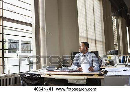 Businessman at desk in office View Large Photo Image Stock Image - Businessman at desk in office. Fotosearch