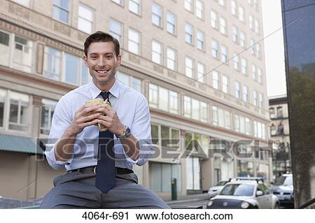 Businessman eating sandwich outside office building View Large Photo Image Stock Image - Businessman eating sandwich outside office building. Fotosearch