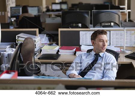 Businessman sitting with legs on desk in office View Large Photo Image Stock Image - Businessman sitting with legs on desk in office. Fotosearch