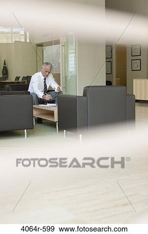 Businessman waiting in office lobby View Large Photo Image Stock Photo - Businessman waiting in office lobby. Fotosearch