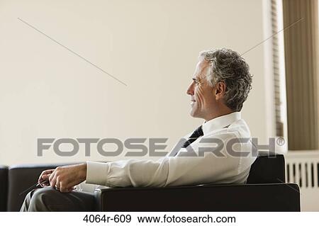 Businessman waiting in office lobby View Large Photo Image Stock Photo - Businessman waiting in office lobby. Fotosearch
