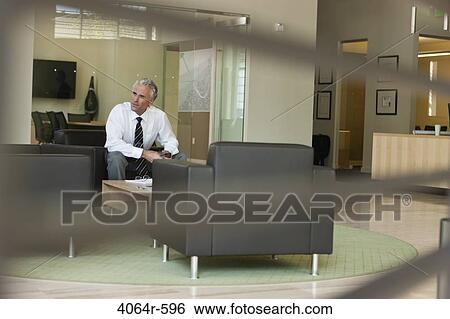 Businessman waiting in office lobby View Large Photo Image Stock Photograph - Businessman waiting in office lobby. Fotosearch