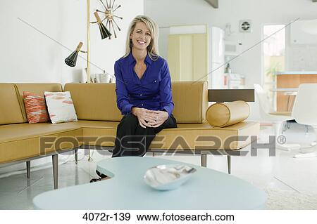 Businesswoman sitting on a couch and smiling View Large Photo Image Stock Photo - Businesswoman sitting on a couch and smiling. Fotosearch